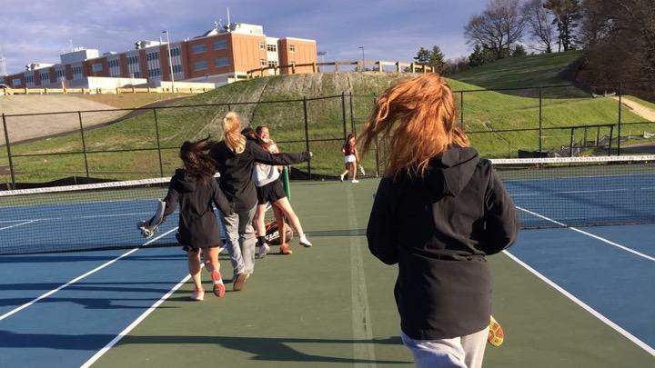 Pictured above is the girls' tennis team celebrating after their win over Concord-Carlisle. “I think [beating CC] showed the girls that we can really make some noise in the state tournament if we keep working hard,” coach Erin Reeves said.