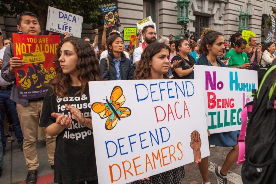 People hold up signs for DACA.