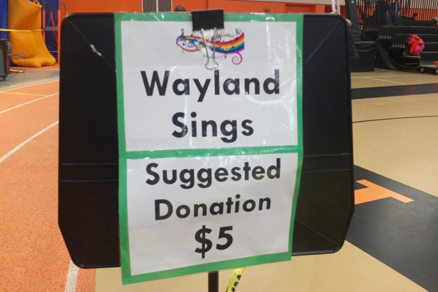 A Wayland Sings donation sign is posted at the entry of the concert.