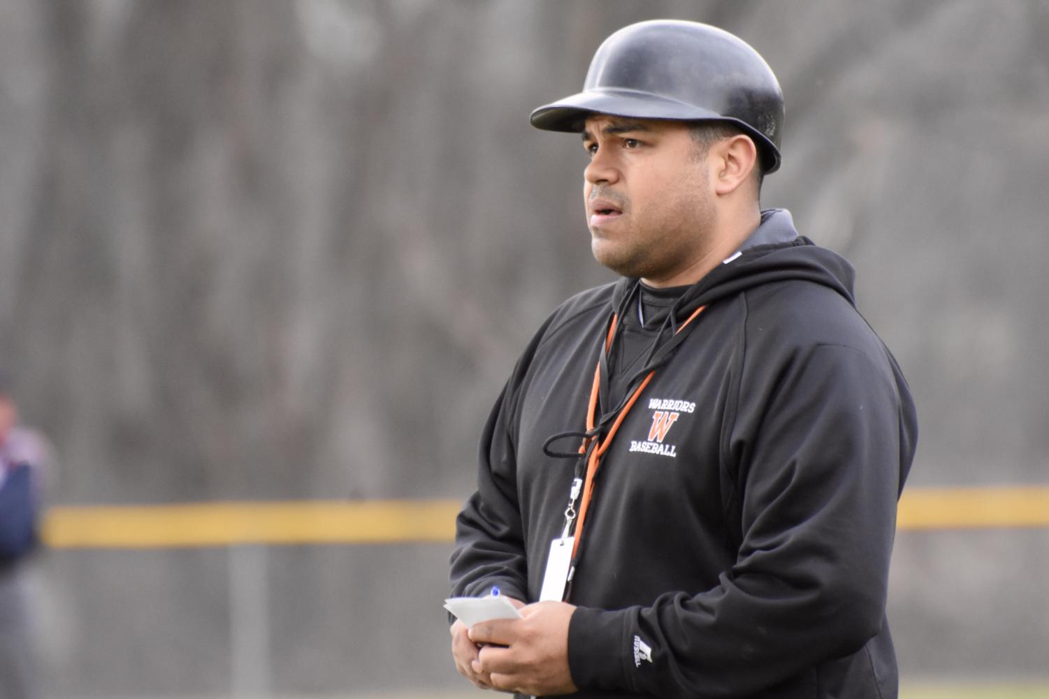 Paul Bonfiglio, the new head baseball coach at Wayland High School, looks down the line and gives signals to his team.