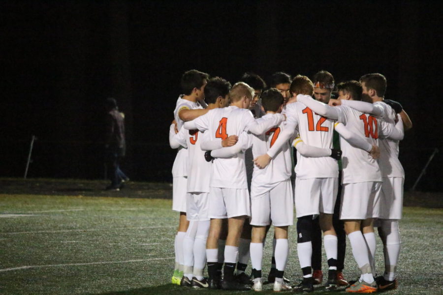 The boys varsity soccer team huddled. It defeated Bedford 5-3 on Sunday after in a double overtime victory. 