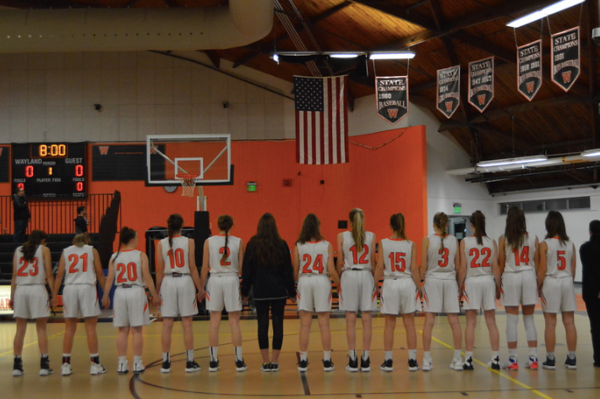 The girls varsity basketball team holds hands for the National Anthem before their game against Boston Latin on December 14. The girls use of practice players helped them to get a spot in the playoffs. When the practice players are there, theres definitely a different level of intensity that comes... it brings in new competition and it kind of makes everyone work a little harder, senior captain Kate Balicki said.