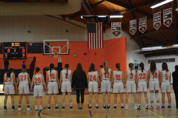 The girls varsity basketball team holds hands for the National Anthem before their game against Boston Latin on 12/14/2018. The girls use of practice players helped them to get a spot in the playoffs. 