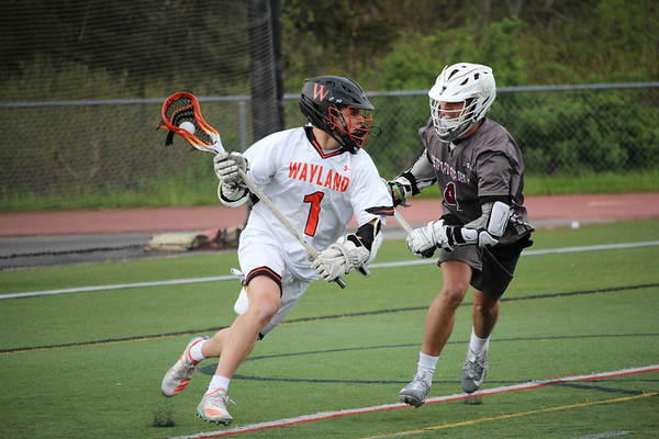 Senior captain Michael Lampert looks to make a pass as he fights off a defender behind the Westford net.