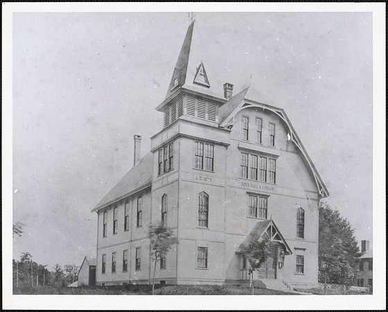 This photograph, circa 1884-1930, shows the Old Town Hall, located at 12 Cochituate Road. It was built in 1878 to serve as the new town hall and was demolished in 1957 and is also the current site of the Grout Heard House. George K. Lewis described the building in his book Growing Up in Wayland: Occasionally, movies were shown on Saturdays at the old Wayland Town Hall, a huge Victorian structure of wood, that stood where the Grout-Heard House does today. The Town Hall had a very large meeting room on the second floor, provided especially for town meetings, but also used for Wayland Garden Club flower shows and a local badminton group.