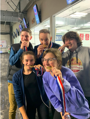 The USA Youth Curling team just won the trails for the Olympics. The four team members and their coach all hold their medals in their mouths to celebrate their big victory.