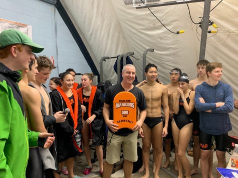 Wayland Warriors swim and dive head coach Mike Foley holds a kickboard after being awarded the 500th and 501st win of his career. Foley accepts this kickboard with the signatures of the athletes and coached who helped him achieve this goal.