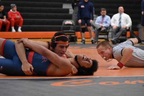 The referee counts back points as Pereira attempts to pin his opponent. The referee is using his second whistle of the day, having broken his first earlier due to exuberant whistling. Pereira, who wrestles at 182 pounds, won the match.