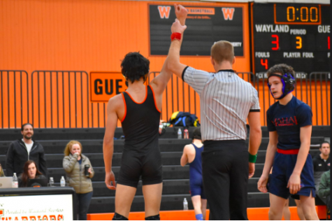 The referee holds up junior Walker Whitehouse's hand after Walker's victory in the match. The wrestling team recently won DCLs.