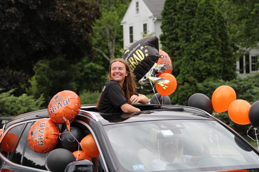 Senior Kayla Poulsen stands out of her decorated car, while smiling at the camera.