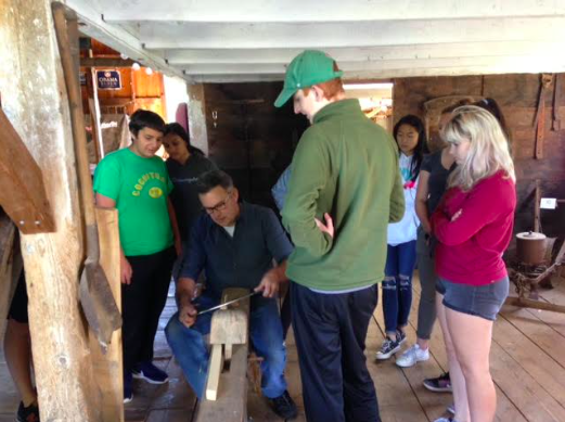 History department head and Attic Archeology teacher Kevin Delaney uses a tool for students at a farm in Sherborn as part of a project on how life was like on a farm. Field studies are an important part of the course and students must be open to taking part in more unconventional forms of learning. “To be part of Attic Archeology, [youve] got to be willing to get dirt under your fingernails and be like ‘I don’t care, I’ll go muck around in the woods and see if we can find something,’” Delaney said.