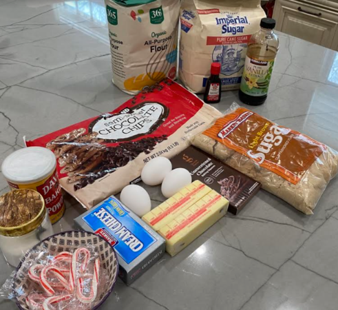 Gather all your ingredients: unsalted butter, chocolate chips, baking chocolate, all-purpose flour, baking powder, salt, eggs, egg yolk, light brown sugar, granulated sugar, vanilla extract, cream cheese, powdered sugar, peppermint extract and crushed candy canes.