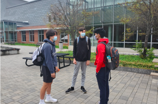 Masked WHS students talk after being let out of school for the day. As of April 27, social-distanced conversations such as these will be able to occur between vaccinated individuals without masks. "I’m happy with not having to wear masks in certain scenarios, like some outdoor gatherings," sophomore Eli Sodickson said. "I will continue to wear one when in the general public, though, even if it’s just walking on the sidewalk."