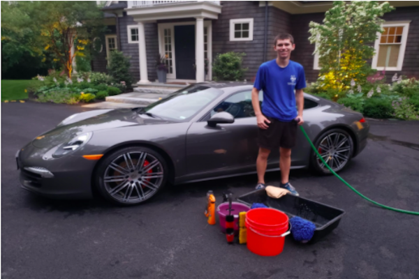 Senior Zach Marto smiles near one of his customers' cars. Since he started Marto’s Mobile Car Care, his business services have expanded greatly. “It started out strictly as only washing cars and it was just me at the beginning,” Marto said. “It eventually evolved into where it is today where we do detailing services, waxing services, and we go on the inside of the cars."