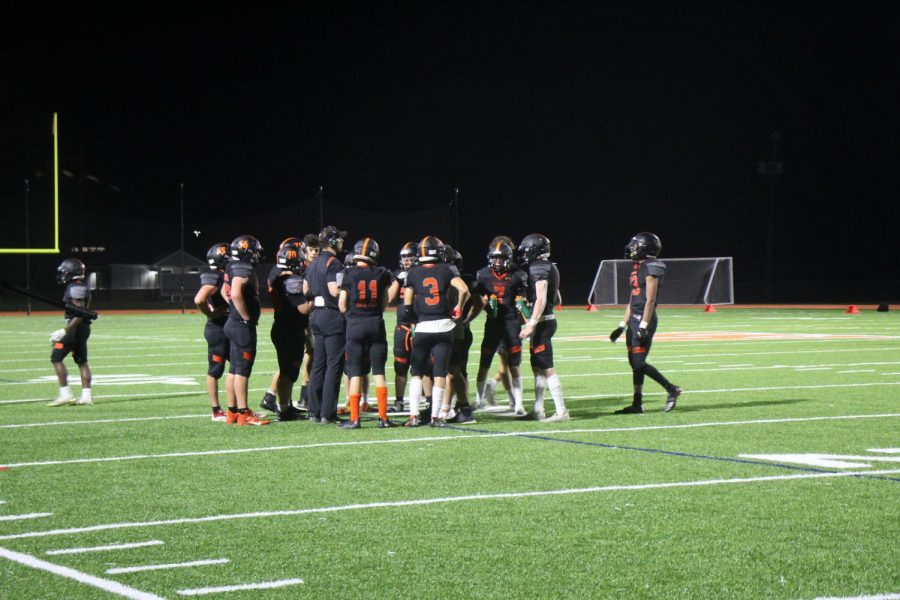 The Wayland offensive line huddles before the play. They strategize about how they are going to score.