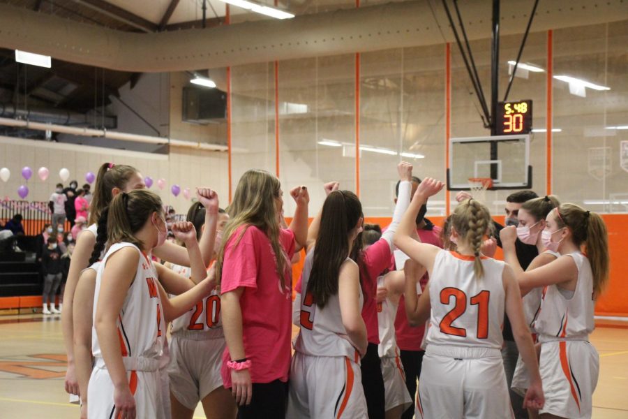 The varsity girls basketball team huddles during their game. Although masks were not required for outdoor sports, all winter sports were required to wear masks this season. 