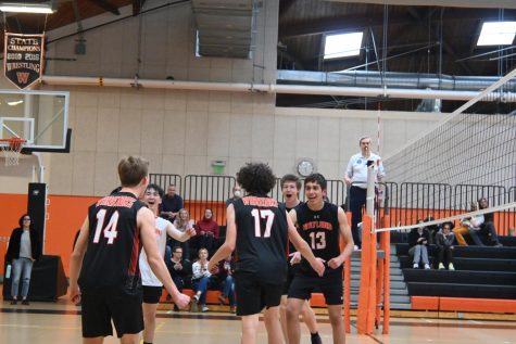 The team strides toward the middle of the court to celebrate winning the second set. In volleyball, a set is played until one team gets to 25 points, with at least a two point difference.