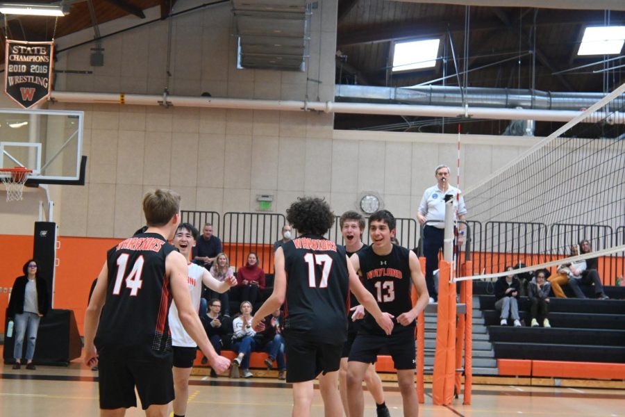 The team strides toward the middle of the court to celebrate winning the second set. In volleyball, a set is played until one team gets to 25 points, with at least a two point difference.