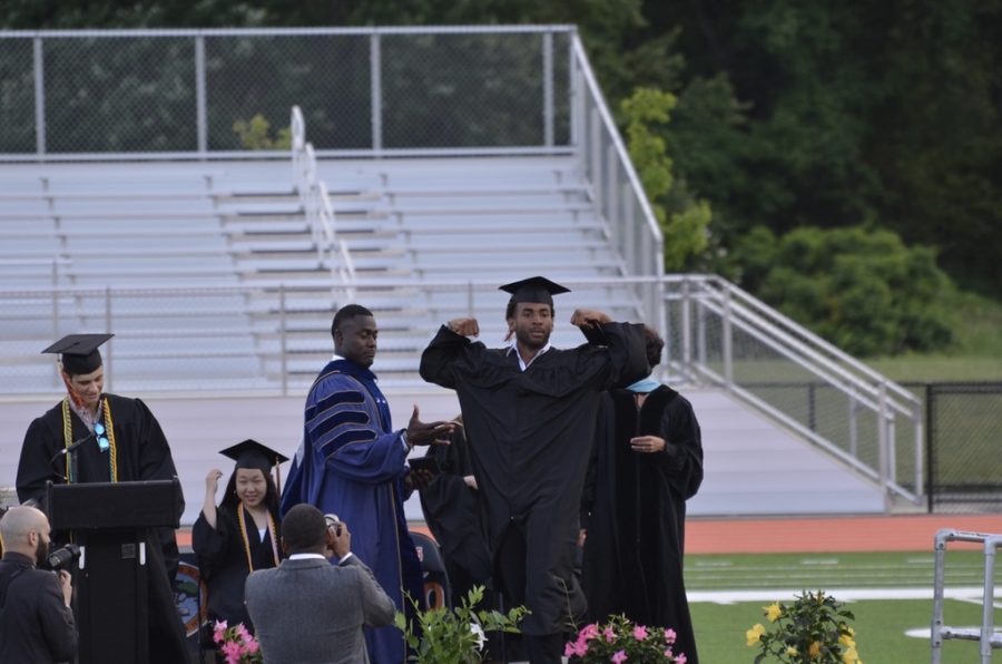 Senior Daniel Bede faces the audience and poses after receiving his diploma and  congratulations from Principal Allyson Mizoguchi and Superintendent Omar Easy.
