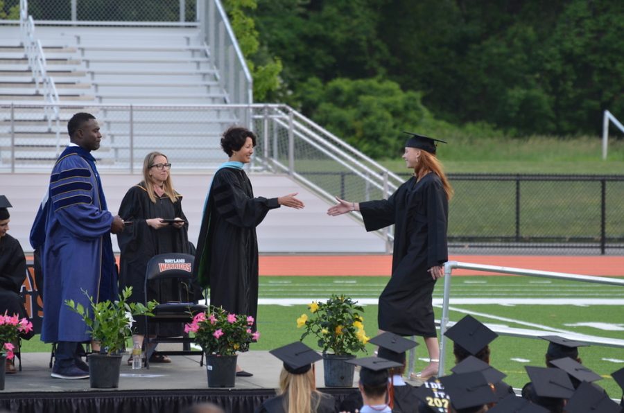 Senior Kate Clifford reaches out to shake hands with Principal Allyson Mizoguchi. Each graduating student was greeted and congratulated by Mizoguchi and Superintendent Omar Easy when they received their diploma.