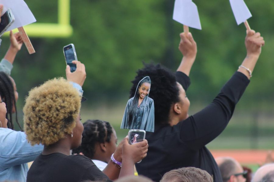 Senior Lauren Grant Lubins family members hold up an image of her as she walks onto the podium to give her speech. Many families made signs with cut-out portraits of graduates to show their support.