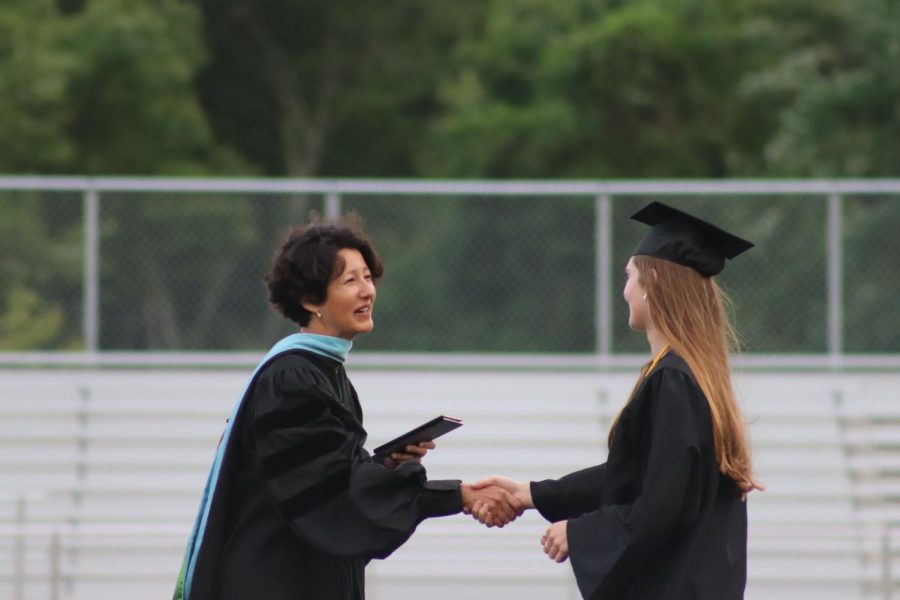 Principal Allyson Mizoguchi shakes senior Phoebe Greenaways hand as she gives Greenaway her diploma. Each graduate shook Superintendent Omar Easy and Mizoguchis hands when getting their diploma.