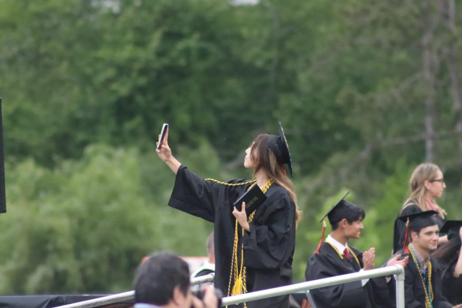 Senior Katherine Kim takes a picture on the podium after receiving her diploma. Some seniors took selfies with the rest of the graduates while standing on the podium.