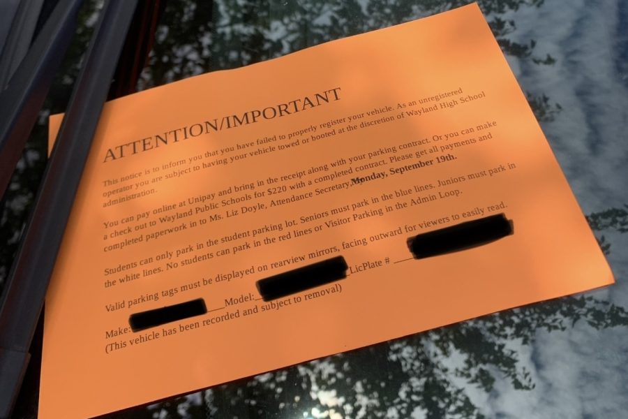 Displayed under the front windshield wiper of cars without parking passes is the bright orange parking pass notice.