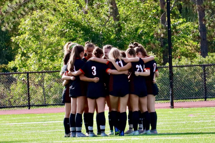 Wayland girls varsity soccer team huddles at the start of their game against Boston Latin on Sep. 21. The team currently holds a 4-3 record with a recent loss to Billerica Memorial on Saturday Sep. 24.
