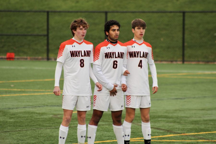 Junior Luke Pythila, senior Nikkie Kapadia and sophomore John Pordage make a wall to defend Hopkintons penalty shot. It was an intense game, well fought but unlucky in the end, Pythila said.