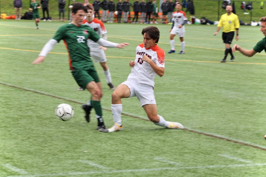 Senior Declan Murphy slides in to kick the ball out of a Hopkinton players possession.