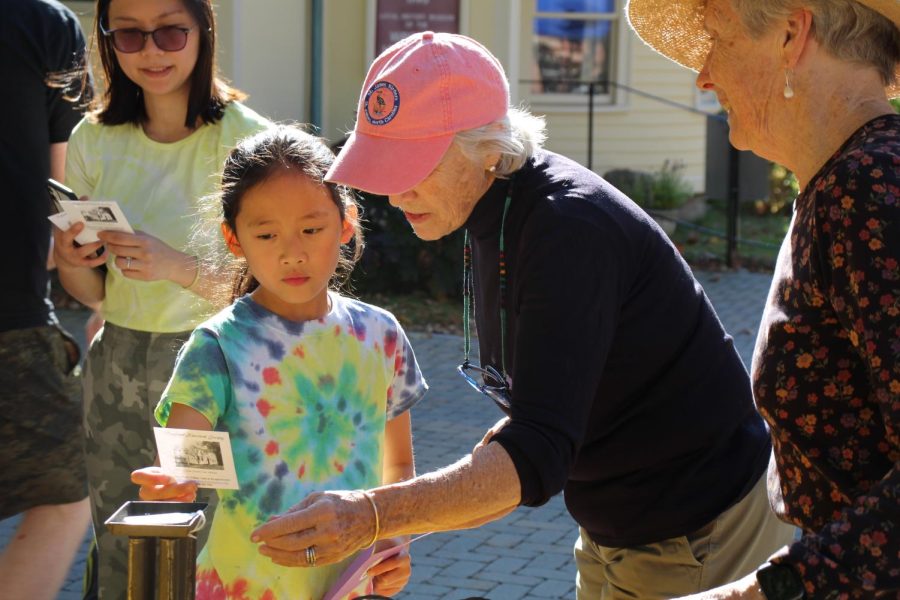A young participant asks a Wayland Historical Society member for help locating her object. For some, finding the object quickly was difficult because of the many objects spread out among three separate tables. The Wayland Historical Society, along with seven other organizations, sponsored the Wayland Amazing Race.