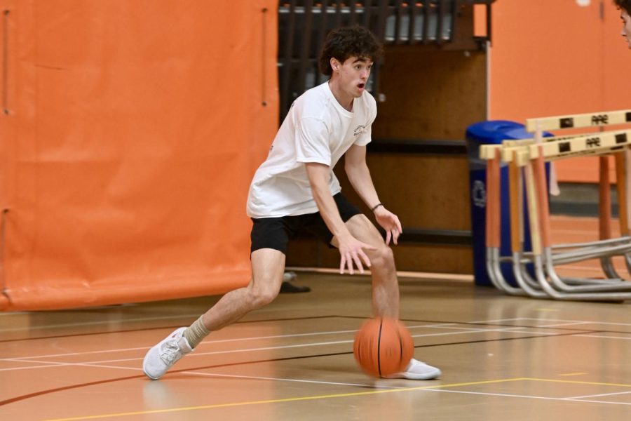 Senior and orange team player Ryan Prince dribbles the ball, looking for an open player to pass to. Each IBL has its own captain and coach. The coaches are varsity basketball players from the girls team and boys team.