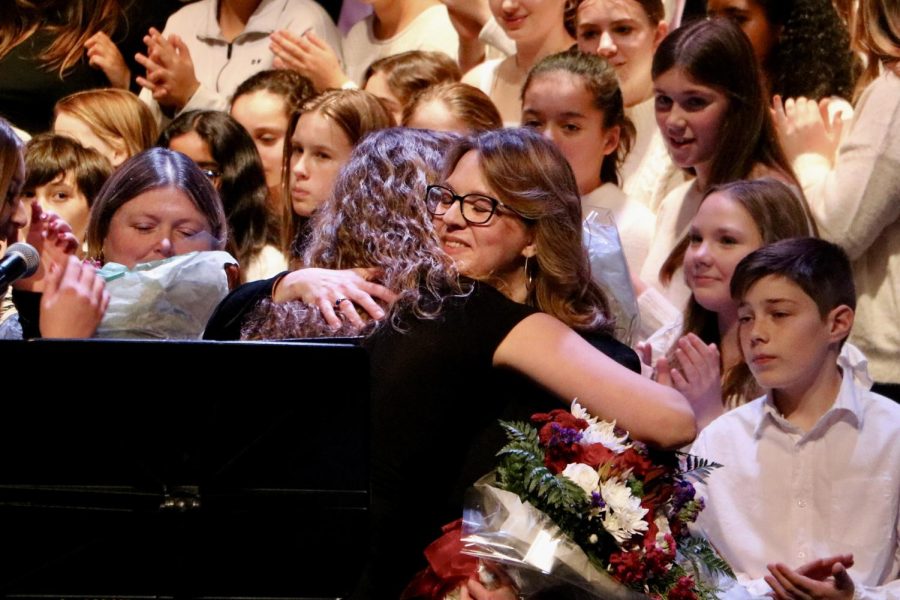Senior Katie Shouten hugs chorus director Rachel Carroll at the Winter Choral Concert on Tuesday, Dec. 13, 2022. The concert brought Wayland Middle School and Wayland High School together. Members of the school’s choir groups serenaded the audience in seven separate groups before coming together for one song to end the concert.