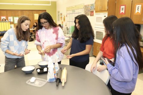 From left to right freshman Julianna McDonald, junior Sophia Verma, freshman Marissa Mendoza and sophomores Melody and Marissa Wong stand together, each grabbing a piece of dough to mold. After senior Eileen Kaewapresert made the pasta dough, the rest of the students got to create the shapes of their choice. “At first, this was only a small group to bond with two special needs students, Melody and Marissa [Wong], because they already had an interest in cooking,” Kaewprasert said. 