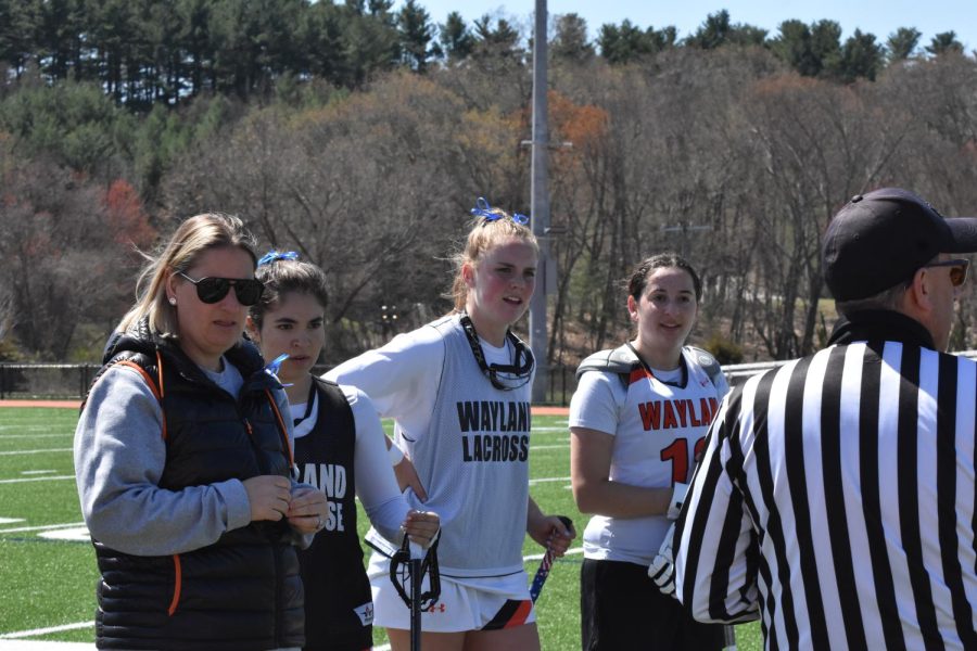 Head coach Ashley Means stands with the captains, seniors Catherine Taxiarchis, Deirdre Brown and Jessie Feist, to talk to the referee and the Winchester captains before the game starts.