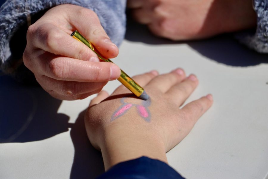 During the WCPA annual egg hunt, a high school volunteer carefully colors in an Easter bunny on a participants hand.