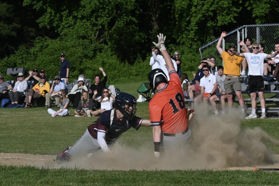 Sophomore Owen Finnegan slides onto the base just as a baseman from the other team reaches him in to tag him out.