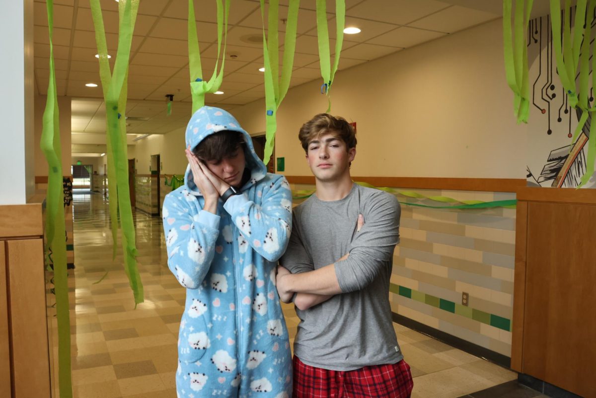 Seniors Charlie Lieb and Andrew Medeiros act asleep while posing in their pajamas and onesie.
