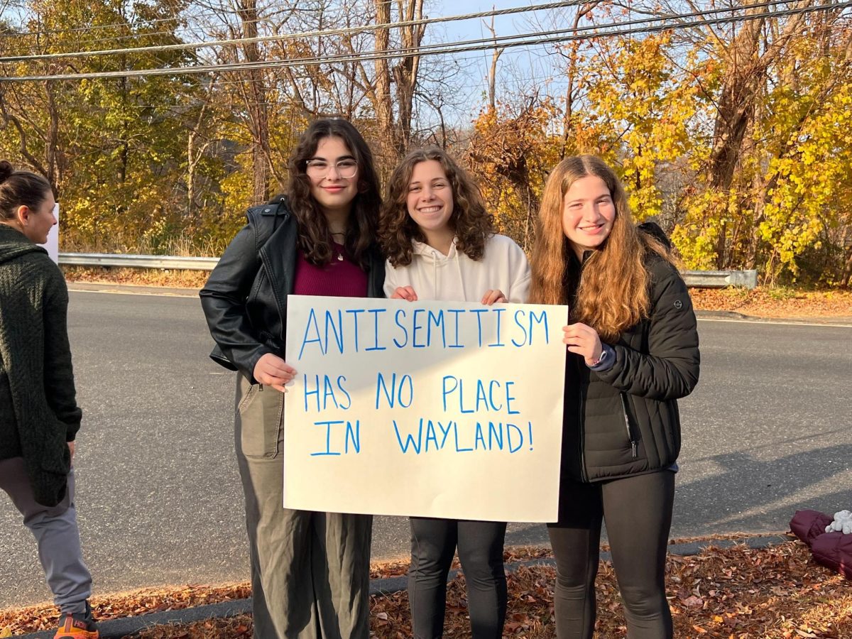 From left to right, Jewish Student Union leaders and juniors Rebecca Grossman, Bella Schreiber and Rachel Goldstone stand together while holding an antisemitism has no place in Wayland sign.