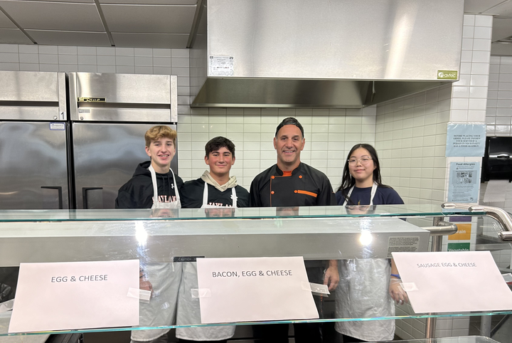 Wellness teacher Scott Parseghian, along with freshman Joshua Magyar, freshman Trevor Rosser and sophomore Emiko Niimi, prepare breakfast sandwiches for the free hot breakfast initiative. “There’s just enough room for three or four people to be [cooking] and get the feeling of if they ever want to run a restaurant or a business where they are behind the grill,” Parseghian said.
