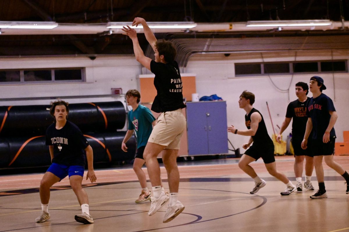 Junior black team player Alex Crawford rises in the air as he shoots the ball from the three-point line.