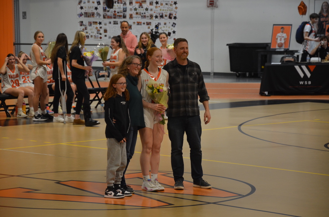 Senior CC Haddad comes together with her family for a photo. Since it was senior night, seniors on the girls varsity basketball team received flowers and posed for photos with their families. 