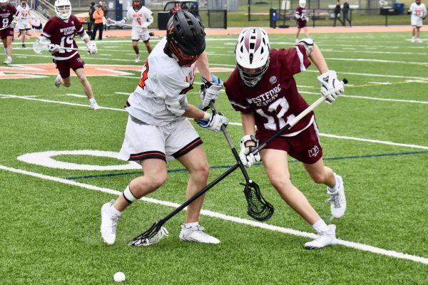 Senior Brandon McCray rushes for a ground ball against a Westford Academy long stick midfielder.