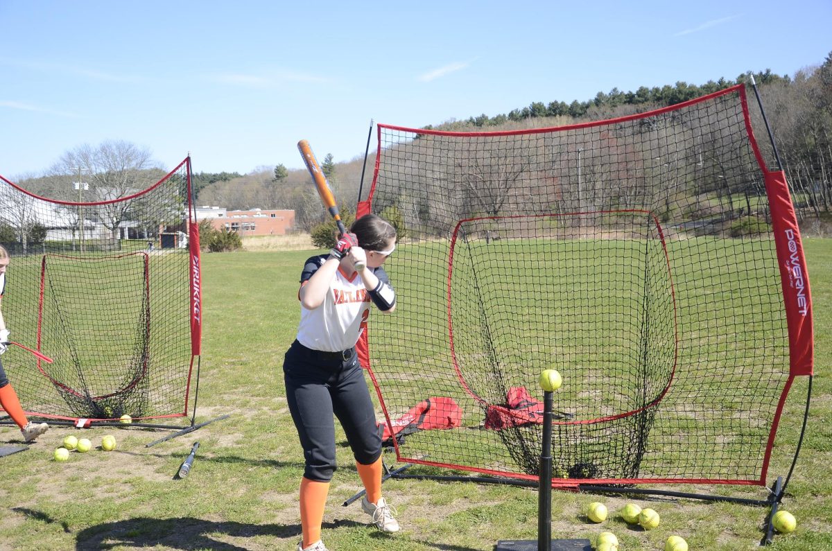 Sophomore Vivi Brevard practices batting the ball into the net on a tee.