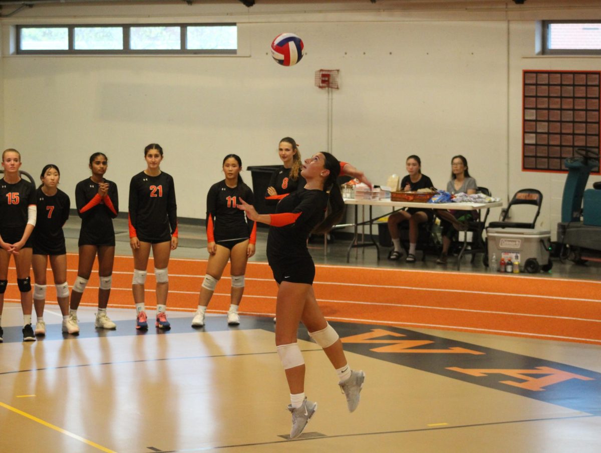 Junior Anna Yalli serves the ball. Along with playing for the Wayland team, Yalli plays for the Slam Volleyball club team.