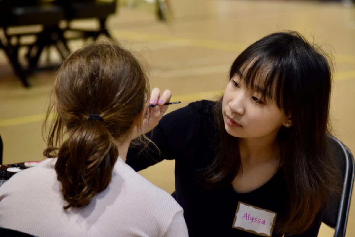 Senior Alyssa Ao, a volunteer for the face painting station, carefully paints the attendees face. Ao is the president of the National Art Honors Society (NAHS), along with senior Tara Sawrikar who is the vice president.