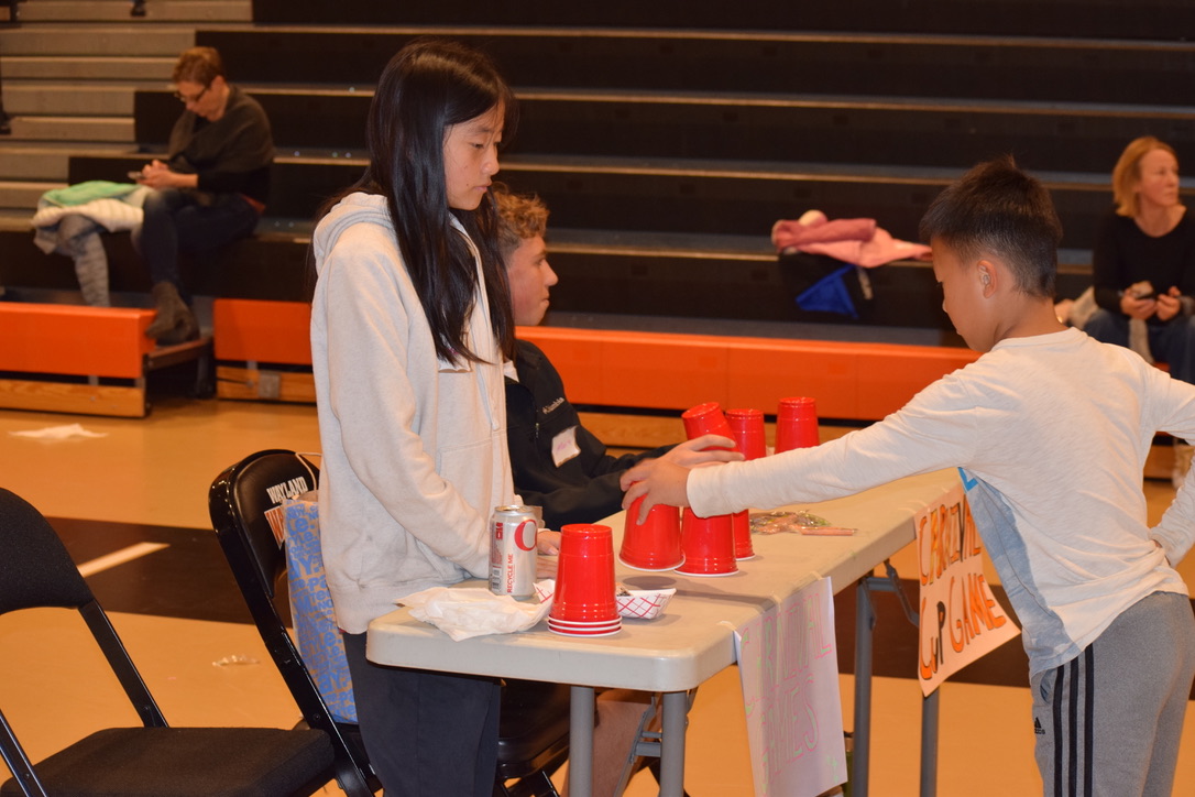 Sophomore Cordia Wang shuffles plastic cups as part of a game for kids to participate in. "Seeing all the kids reactions to the different tricks I did was really fun," Wang said.