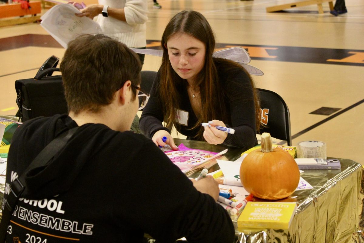 Senior Sofia Simmons fills in a coloring sheet while volunteering as a NHS member. Volunteers were asked to either wear all black or to dress up as something. For Simmons, she chose to dress as a fairy.