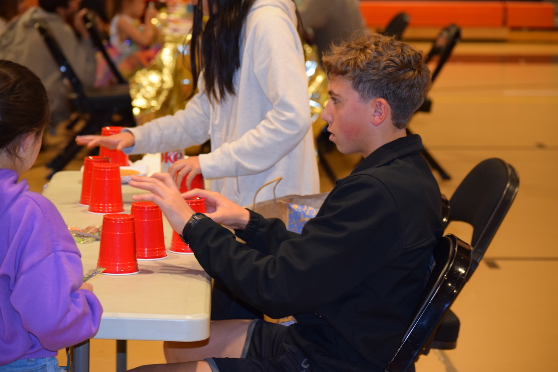 Junior Mark Altreuder shuffles cups with prizes underneath, and kids try to guess which cup has the prize. Altreuder volunteered along with sophomore Cordia Wang at this station.